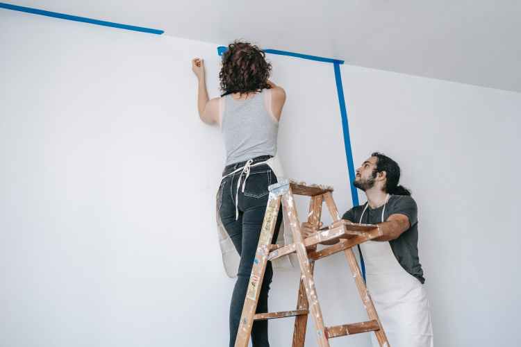 woman on a stepladder painting a wall